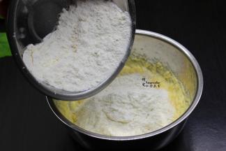 将过筛的面粉、泡打粉，倒入打发好的黄油里，用刮刀稍微拌均。