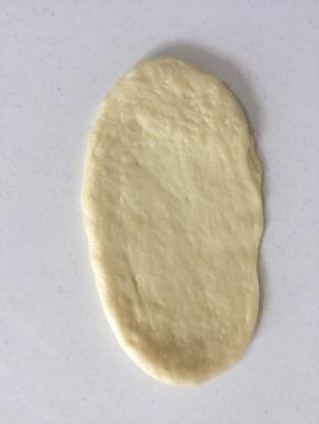 取一个小面团拍扁排气，略擀成长椭圆形。