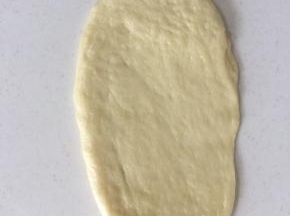 取一个小面团拍扁排气，略擀成长椭圆形。