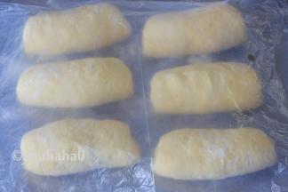 醒发后的面团翻面、拍扁、上下擀开，再自上往下卷起，依次做好6个面团，继续改保鲜膜醒发15分钟左右。