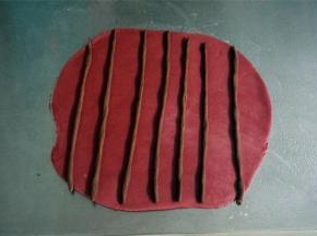 把红色的面团擀成21*22的面片，随意放上棒状的可可面团。