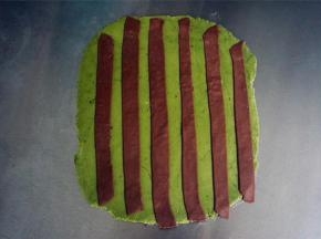 把可可色的条状面片随意摆放在绿色的面片上，然后用擀面杖稍微压一压。