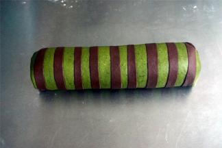 将可可条绿色面片包裹住原色的面团，包裹的方向与可可面条平衡，我图片所示是错误的垂直方向，注意了。因为包好了才发现，只能将错就错了。