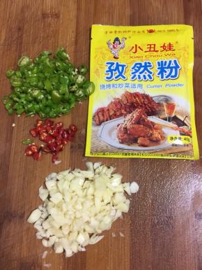 蒜瓣剥皮剁成蒜末，青尖椒和红辣椒切成圈儿，准备好孜然粉备用。