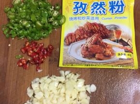 蒜瓣剥皮剁成蒜末，青尖椒和红辣椒切成圈儿，准备好孜然粉备用。
