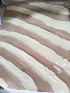 裱花袋尖端剪小口斜着将面糊交替挤进烤盘。挤好端起烤盘震出气泡。