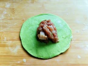 取一块面团，用擀面杖擀圆，加入肉馅。