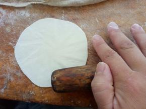 擀面杖像图中这样放到烧麦皮边缘，边擀边转动烧麦皮