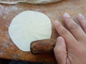 擀面杖像图中这样放到烧麦皮边缘，边擀边转动烧麦皮