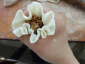 像图中这样利用虎口将烧麦边缘微微收紧，另一只手将馅料往里压一下，虎口收紧，压出腰线来，一个烧麦就包好了