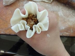 像图中这样利用虎口将烧麦边缘微微收紧，另一只手将馅料往里压一下，虎口收紧，压出腰线来，一个烧麦就包好了