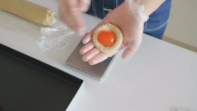 将莲蓉馅压扁后弄个小窝，放上咸蛋黄