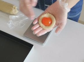 将莲蓉馅压扁后弄个小窝，放上咸蛋黄