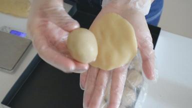 将饼皮压扁，放上莲蓉蛋黄
