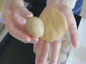 将饼皮压扁，放上莲蓉蛋黄