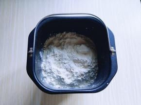 除黄油外的食材全部加入面包桶，盐和糖对角放，鸡蛋1个，奶粉，再加入高筋面粉，最后再面粉的顶端挖个洞，把酵母粉加入洞洞里，再用周边的面粉盖起来。