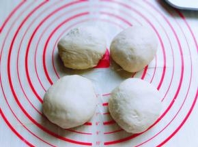 发酵好的面团从面包机取出，盖上保鲜膜排气10分钟，再分割成4等份，揉圆。盖上湿布醒10分钟。