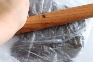 用擀面杖，压碎，多压几次越碎越好。当然这里也可以用料理机直接把饼干打碎。