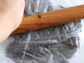 用擀面杖，压碎，多压几次越碎越好。当然这里也可以用料理机直接把饼干打碎。