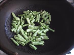 将豆角放入锅中煸炒。