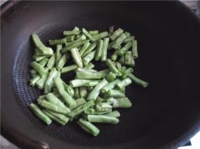 将豆角放入锅中煸炒。