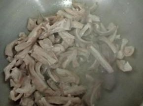 热锅凉油下蒜头，煸炒片刻后倒入猪肚，翻炒均匀。