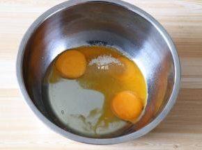 剩余10g白糖倒入蛋黄中，再倒入玉米油，搅拌均匀；