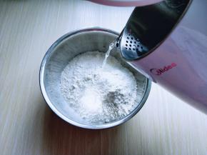 面粉放在容器中，美的电水壶烧开水。分次加入开水。用筷子搅成絮状。不烫手时再揉成面团。盖上保鲜膜醒15分钟。