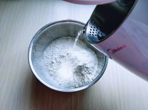 面粉放在容器中，美的电水壶烧开水。分次加入开水。用筷子搅成絮状。不烫手时再揉成面团。盖上保鲜膜醒15分钟。