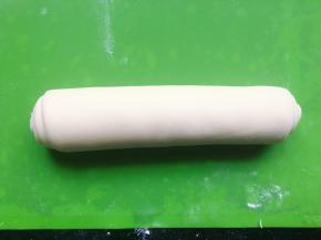 并在表面刷上一层水，从面片的一侧卷起来，卷成长条形，用手从中间向两边搓长。接着将另一块面团整成长条状。