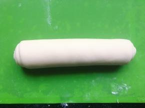 并在表面刷上一层水，从面片的一侧卷起来，卷成长条形，用手从中间向两边搓长。接着将另一块面团整成长条状。