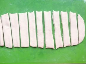 然后用刮板切成宽度相等的长条形，比锅子短的尺寸即可，否则炸的时候面胚长了，锅子小了就不合适。