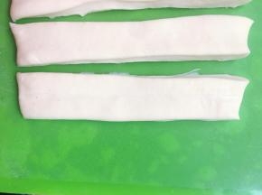 将两条长条形的面胚重叠在一起，两条面胚之间可以沾点水，这样粘的更紧实，炸的时候不容易散开。