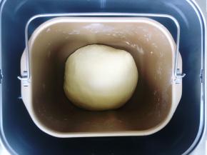 启动面包机和面程序，不要盖盖子，揉至面团呈光滑的状态后加入软化的黄油，继续揉至撑开面团是有韧性的薄膜状态。这里要说明的是揉面的时候不要盖盖子是因为面包机操作时会发热，如果盖上盖子，很容易使面温升高。