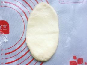 取一个松弛好的小面团按扁，用擀面棍擀成长方形。