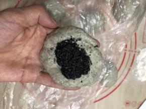 把面团按压成中间厚周边薄，码上适量的黑芝麻，
这个黑芝麻没称，我用勺子挖的，馅的量按个人喜欢
