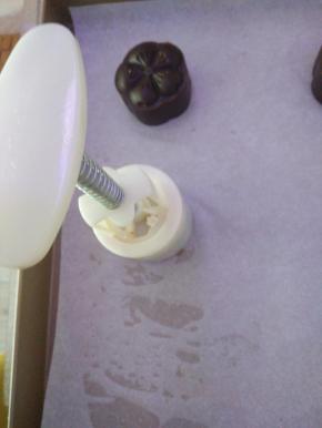 包好的饼坯放入模具，尖角朝外，放在铺好油纸的烤盘上。左手压紧模具底部，右手从上向下压手柄，压实停留几秒，让花纹定型。