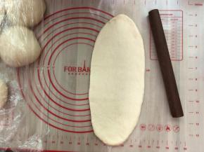 取一个松弛好的面团，擀开边上的气泡拍掉，翻面，自上往下卷起