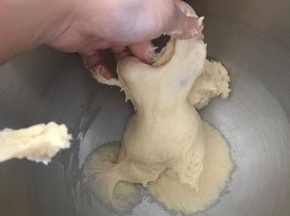 搅打15分钟左右，停下厨师机观察面团组织。面团揉至有延展性和粗膜的时候，加入黄油。