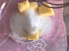 面团发酵的同时，我们可以制作椰蓉馅料。将室温软化的黄油和细砂糖用手动打蛋器搅打均匀。