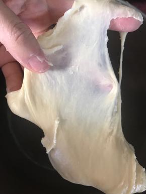 大约10分钟左右，停下来，将厨师机桶边缘的黄油和面钩顶端搅打不到的面团拨下来，继续5档搅打。10分钟左右，停下来观察面团组织，出现了手套薄膜，就可以停下来了。