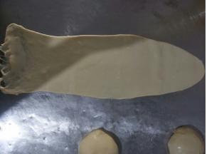 取一个面团，擀长，底部弄薄一点，如图