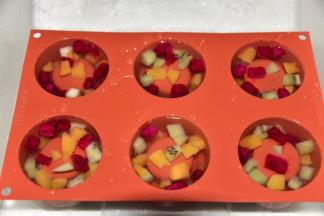 将糖水倒入学厨的模具中，再投入水果