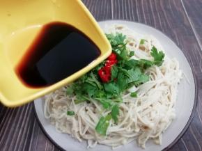 在把生抽和香醋均匀的倒在上面，锅里加入少许的油烧热后把油泼在金针菇上