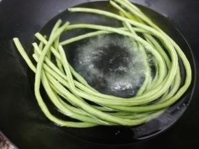 锅里加入适量的水，再加入少许盐和油大火烧开后，把洗干净的长豆角放入锅中焯熟