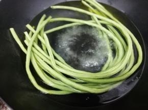 锅里加入适量的水，再加入少许盐和油大火烧开后，把洗干净的长豆角放入锅中焯熟