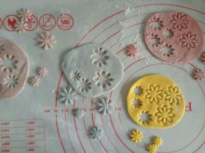 步骤8中剩下的各色面团分别揉一揉，擀成薄片，用压花器压出花朵的形状