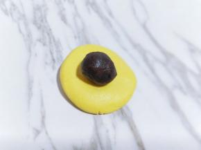 取一小块面团，用手心压扁，再放上豆沙馅，包起来，捏紧！