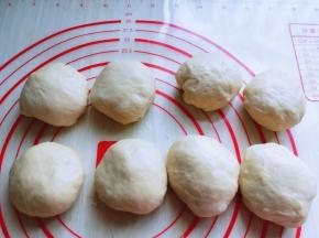 发酵好的面团从面包机取出，盖上保鲜膜排气10分钟，再分割成小面团，揉圆。盖上湿布醒10分钟。