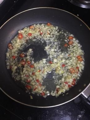 锅烧热倒入适量的油，放入蒜末，姜末，红尖椒圈儿爆香。